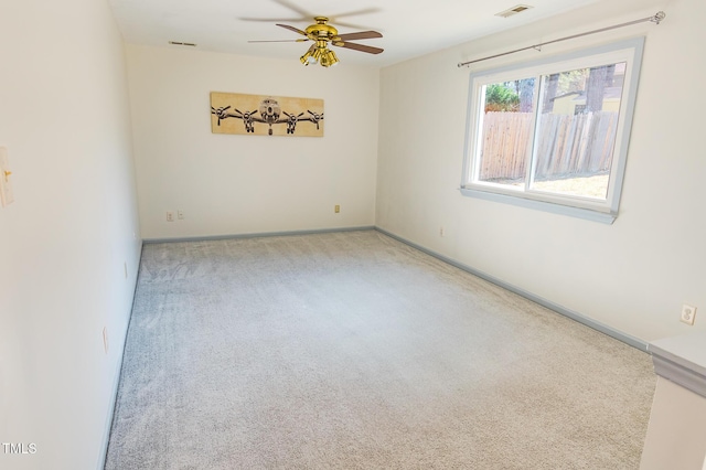 carpeted empty room with visible vents, baseboards, and ceiling fan