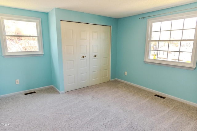 unfurnished bedroom featuring a closet, carpet flooring, baseboards, and visible vents