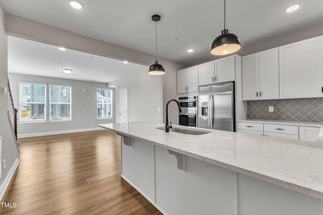 kitchen featuring a sink, white cabinets, tasteful backsplash, and stainless steel appliances