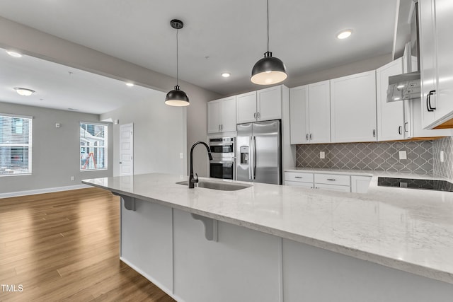 kitchen with backsplash, ventilation hood, light stone counters, appliances with stainless steel finishes, and white cabinetry