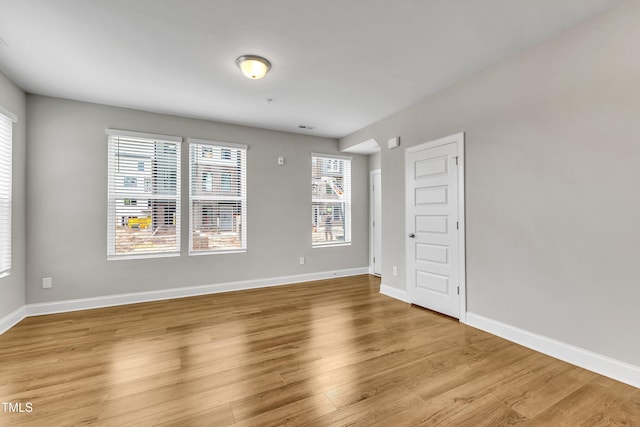 spare room featuring light wood-type flooring, baseboards, and visible vents