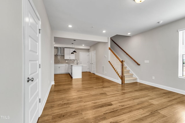 unfurnished living room featuring stairway, visible vents, baseboards, light wood-style flooring, and recessed lighting