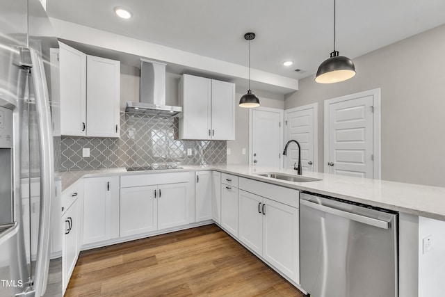 kitchen featuring light wood-style flooring, a sink, appliances with stainless steel finishes, white cabinetry, and wall chimney exhaust hood