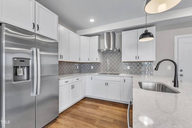 kitchen with light wood-type flooring, a sink, stainless steel fridge, wall chimney range hood, and black electric cooktop