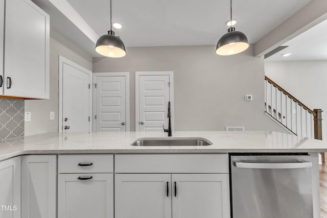 kitchen with light stone countertops, visible vents, a sink, white cabinets, and stainless steel dishwasher