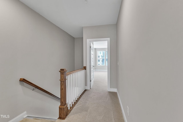 hall with an upstairs landing, carpet flooring, and baseboards