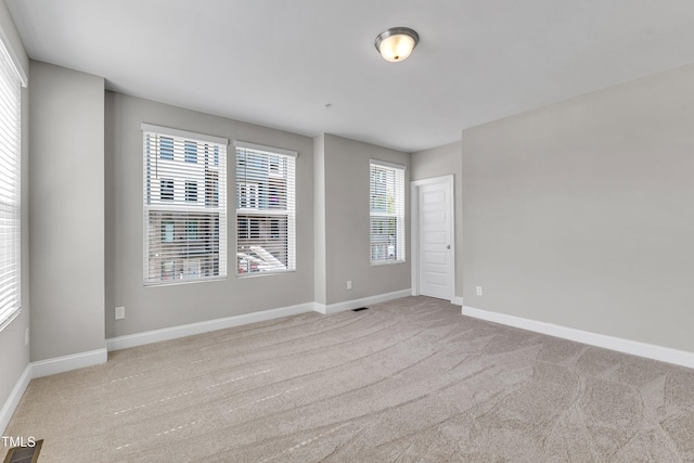 empty room featuring visible vents, carpet floors, and baseboards