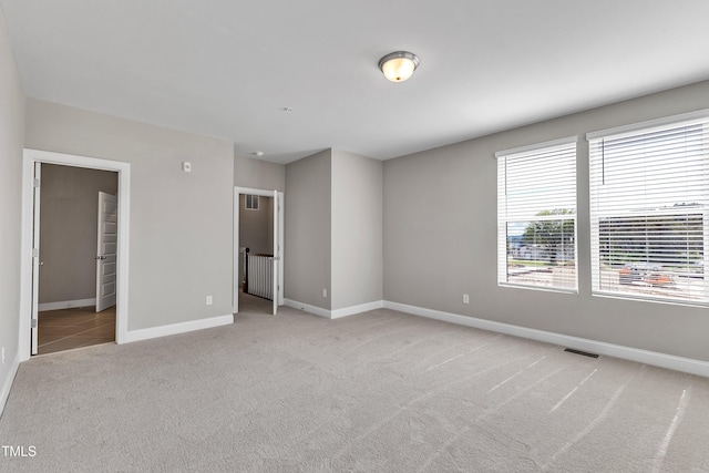 unfurnished bedroom with baseboards, visible vents, and light carpet