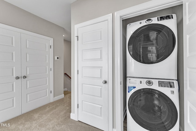 clothes washing area with stacked washer / dryer, carpet flooring, laundry area, and baseboards