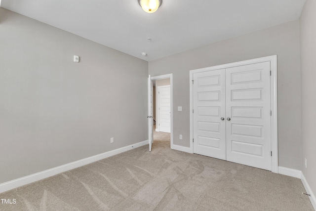 unfurnished bedroom featuring carpet, baseboards, and a closet