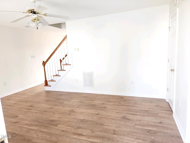 unfurnished living room featuring light wood-type flooring, visible vents, a ceiling fan, baseboards, and stairs