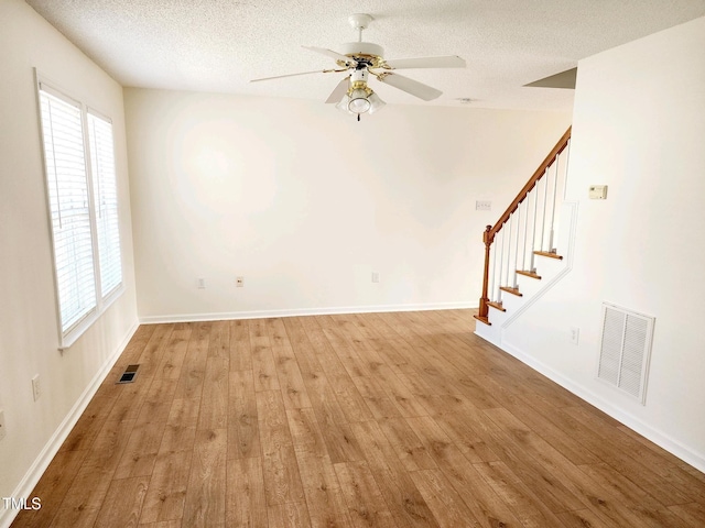 unfurnished room with stairs, light wood-style floors, visible vents, and a healthy amount of sunlight