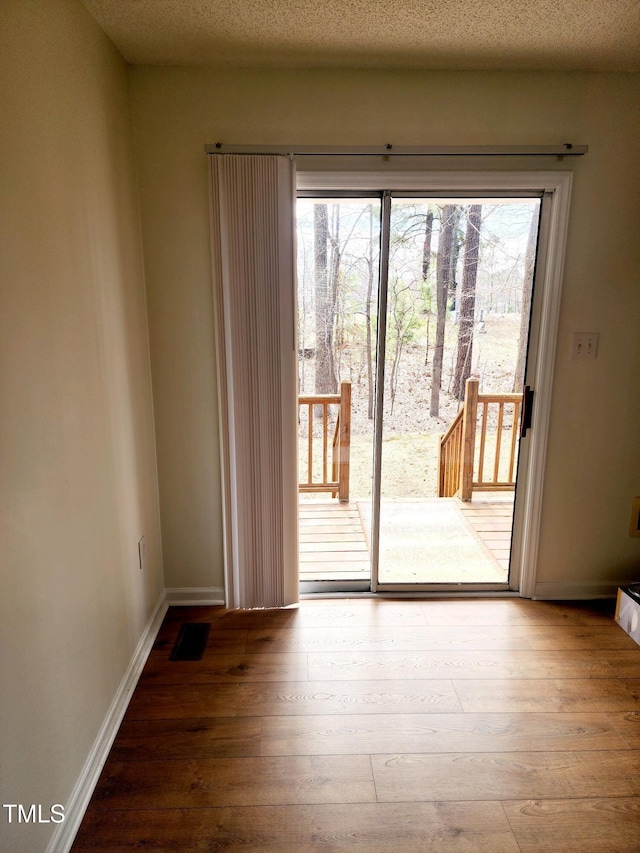 doorway featuring hardwood / wood-style flooring, plenty of natural light, and baseboards