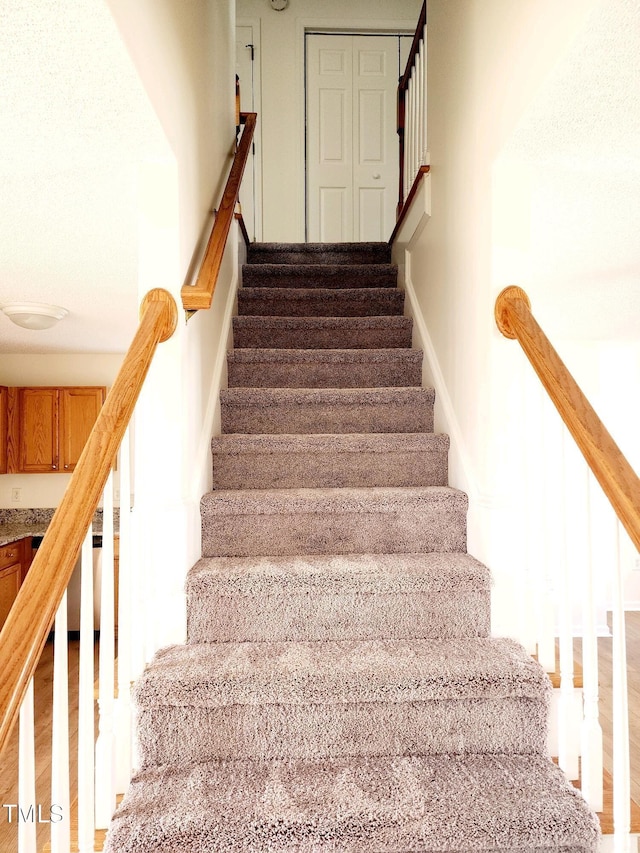 stairway with wood finished floors and baseboards