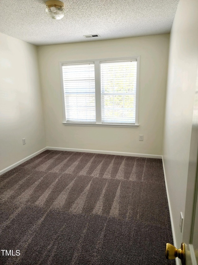 carpeted empty room featuring baseboards, visible vents, and a textured ceiling