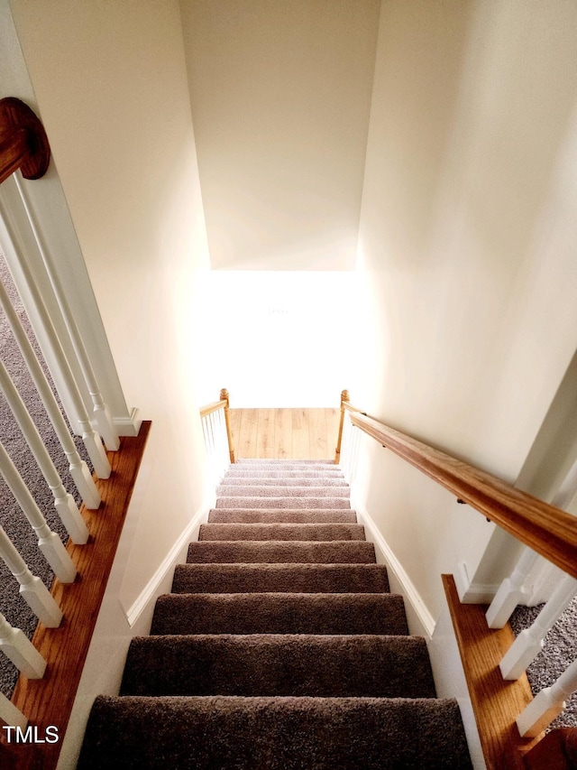 staircase with baseboards and wood finished floors