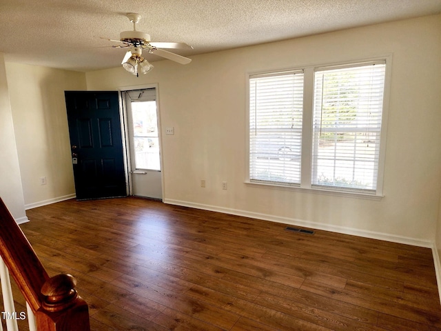 entryway with visible vents, dark wood-type flooring, ceiling fan, baseboards, and a textured ceiling