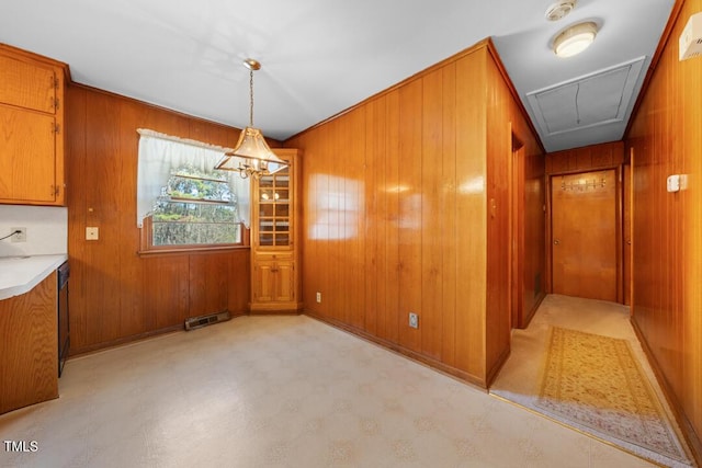 unfurnished dining area featuring attic access, light floors, and wood walls