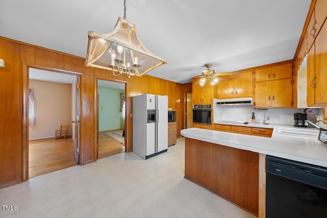 kitchen with under cabinet range hood, brown cabinets, black appliances, and light countertops