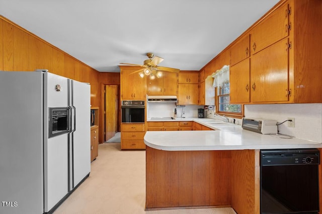 kitchen featuring under cabinet range hood, light countertops, a peninsula, brown cabinetry, and black appliances