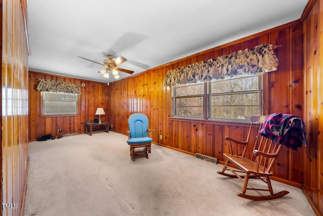 living area with visible vents, wood walls, a ceiling fan, and carpet floors