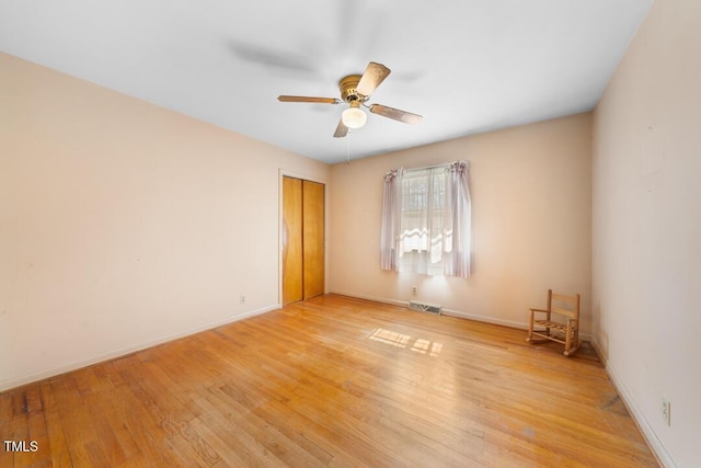 empty room featuring visible vents, a ceiling fan, light wood-type flooring, and baseboards