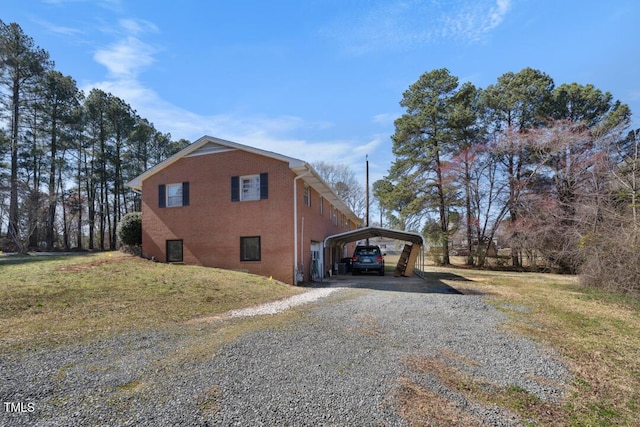 view of property exterior with brick siding, a carport, and driveway