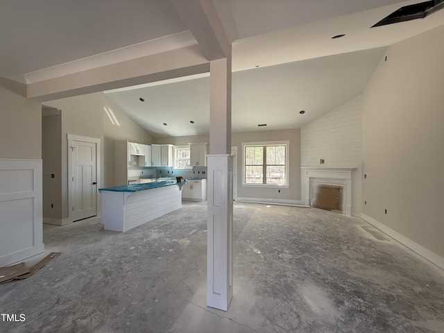 unfurnished living room featuring baseboards, high vaulted ceiling, and a fireplace