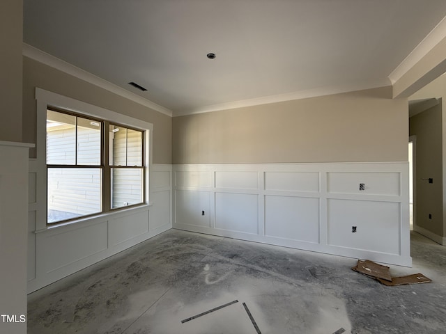 empty room with a decorative wall, crown molding, visible vents, and a wainscoted wall