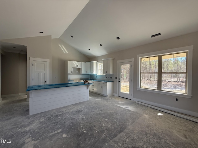 kitchen with baseboards, a kitchen island, white cabinets, and high vaulted ceiling