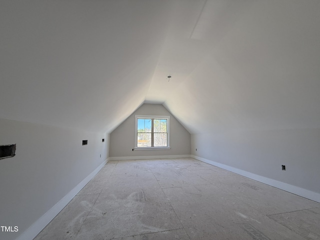 additional living space featuring baseboards and lofted ceiling