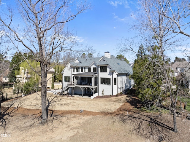 rear view of property with stairway and a chimney