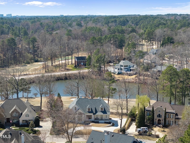 drone / aerial view featuring a wooded view, a water view, and a residential view