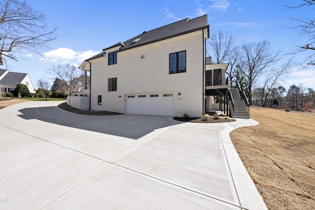 exterior space with stairway, an attached garage, and concrete driveway