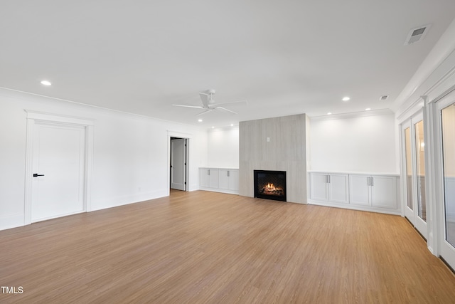 unfurnished living room featuring visible vents, light wood-style flooring, ceiling fan, ornamental molding, and a large fireplace