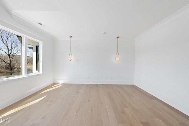 empty room featuring visible vents, baseboards, light wood-style floors, and ornamental molding