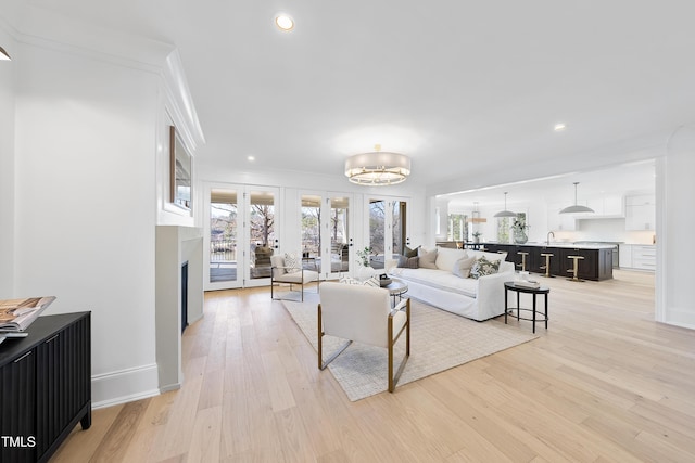 living room featuring light wood-type flooring, recessed lighting, french doors, crown molding, and baseboards