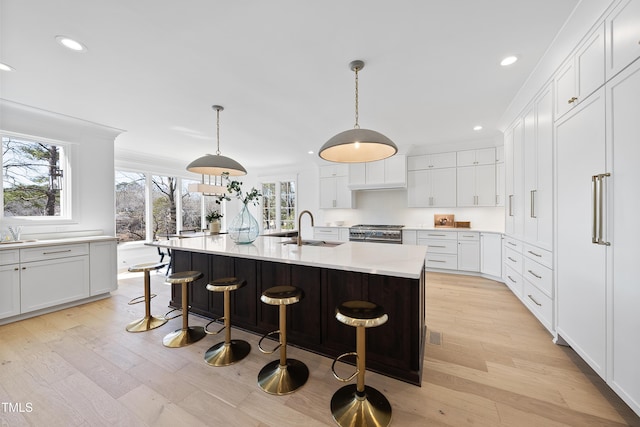 kitchen with a sink, light countertops, white cabinetry, and high end stove