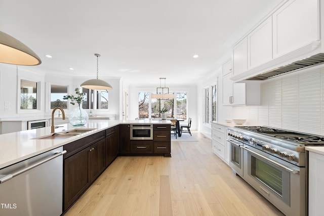 kitchen with a sink, light countertops, white cabinets, dark brown cabinetry, and appliances with stainless steel finishes