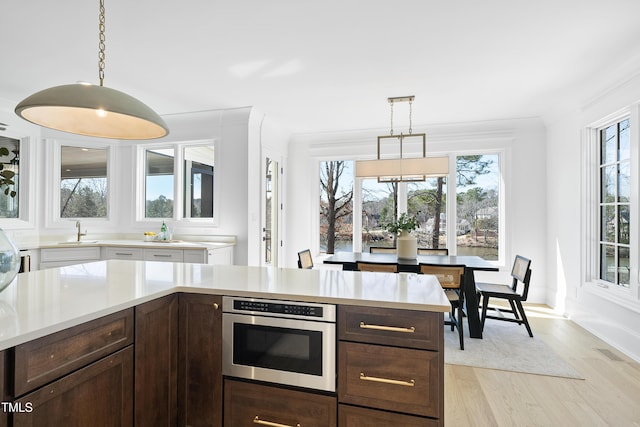 kitchen with a sink, visible vents, dark brown cabinetry, and light countertops