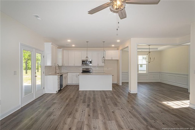 kitchen with appliances with stainless steel finishes, open floor plan, wood finished floors, and a ceiling fan