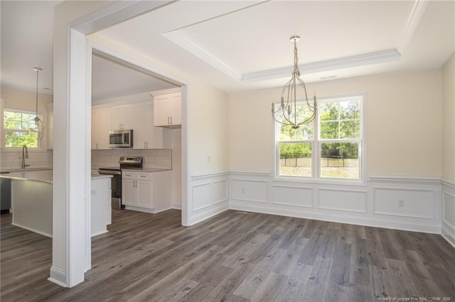 unfurnished dining area featuring dark wood-style floors, plenty of natural light, an inviting chandelier, and a tray ceiling