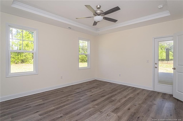 empty room featuring dark wood-type flooring, ornamental molding, ceiling fan, and a tray ceiling
