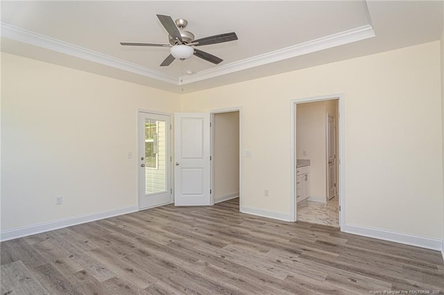 unfurnished bedroom with crown molding, baseboards, connected bathroom, and light wood-style floors