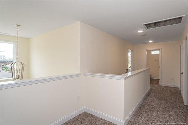 corridor with an upstairs landing, visible vents, carpet, and baseboards