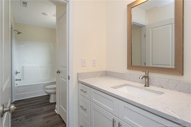 full bathroom with wood finished floors, bathing tub / shower combination, toilet, vanity, and visible vents