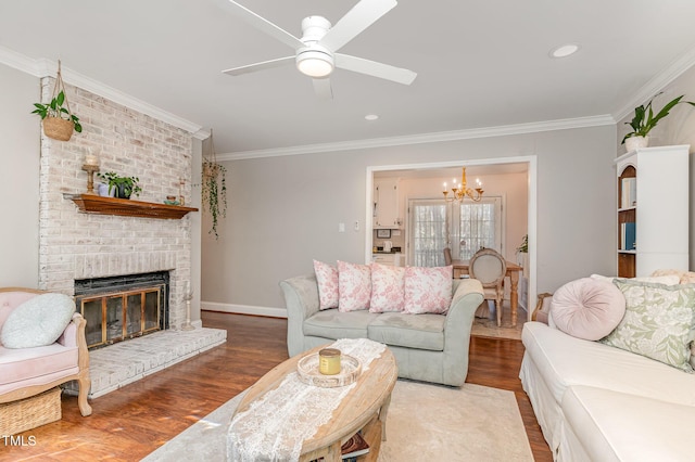 living area with a brick fireplace, crown molding, baseboards, ceiling fan with notable chandelier, and wood finished floors