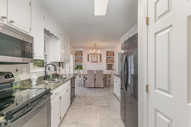 kitchen featuring a notable chandelier, marble finish floor, black appliances, a sink, and white cabinetry