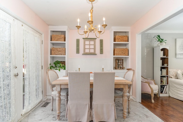 dining space featuring a chandelier, built in features, visible vents, and wood finished floors