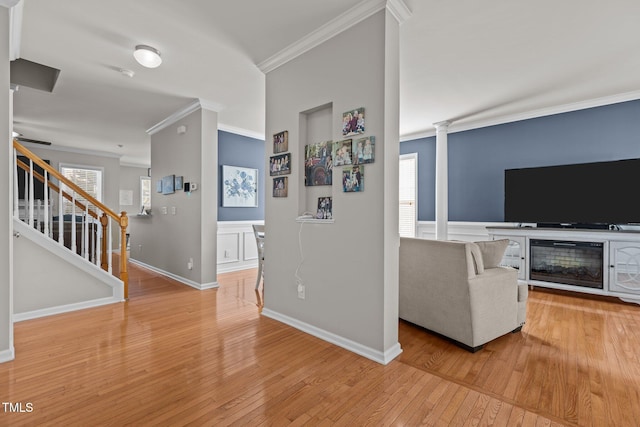 living room with decorative columns, baseboards, light wood-style flooring, and crown molding